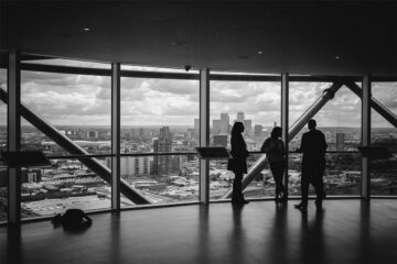 A group of healthcare administration professionals speaking near large windows