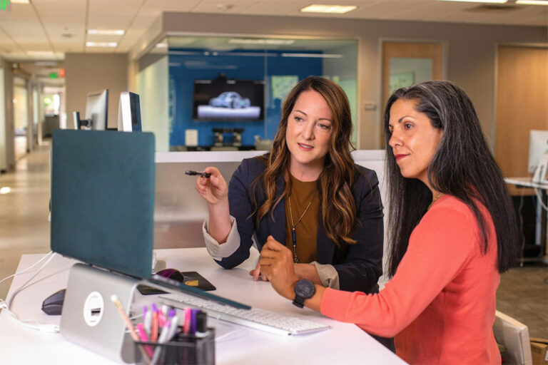 Two healthcare administrators looking at a monitor and discussing timely filing limits
